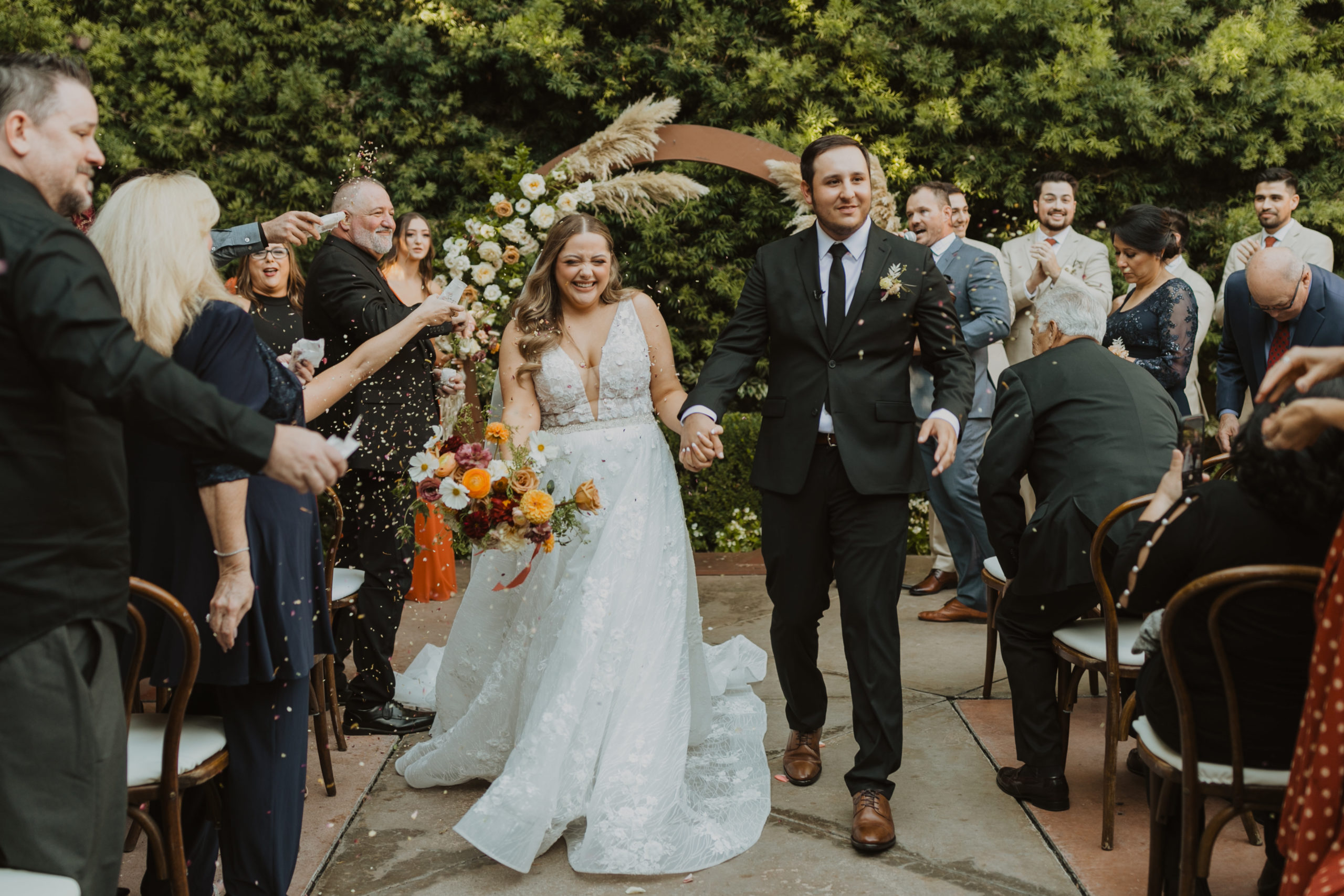 bride and groom are holding hands while walking down the aisle