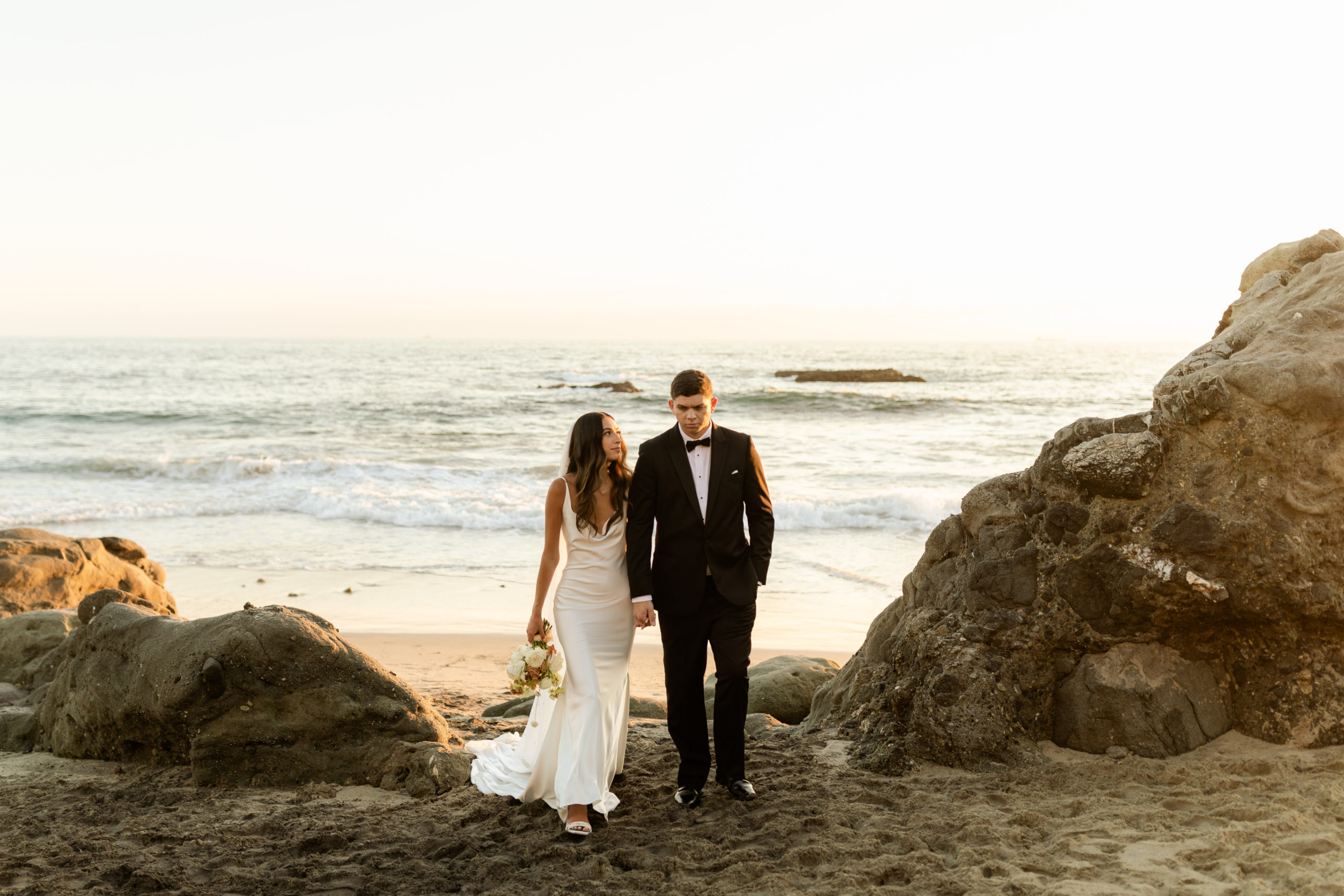 shot of the couple under cliffside on the beach
